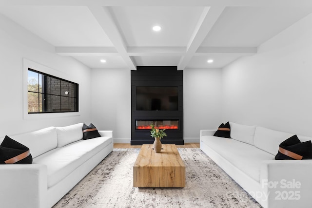 living room featuring coffered ceiling, light hardwood / wood-style flooring, a large fireplace, and beamed ceiling