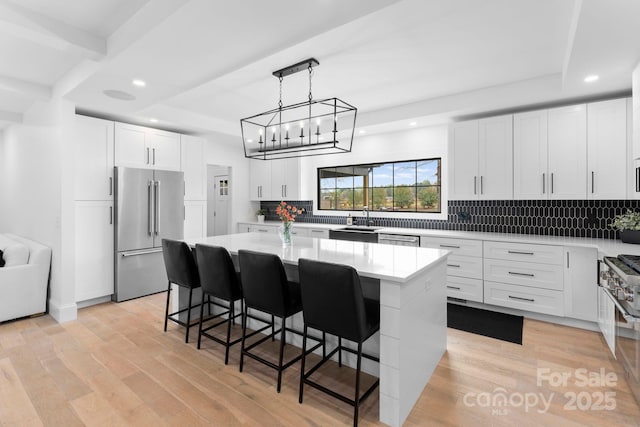 kitchen with appliances with stainless steel finishes, a kitchen breakfast bar, white cabinets, a kitchen island, and a raised ceiling