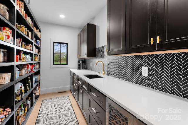 kitchen with tasteful backsplash, dark brown cabinets, sink, and beverage cooler