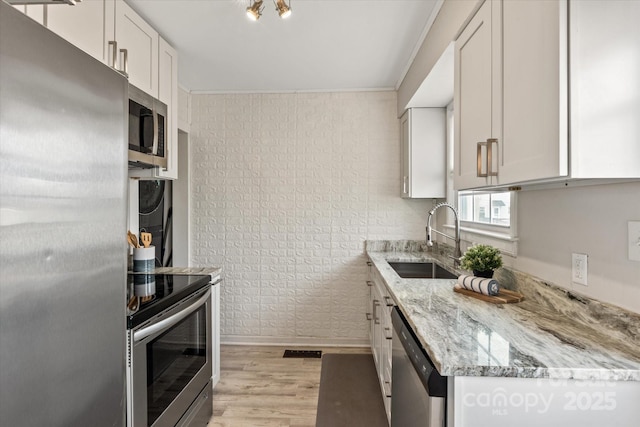 kitchen featuring sink, light hardwood / wood-style flooring, stainless steel appliances, light stone counters, and white cabinets