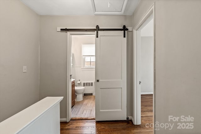 corridor with radiator, dark wood-type flooring, and a barn door