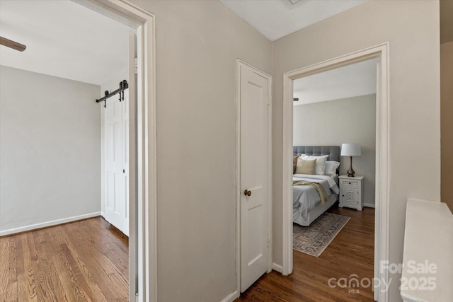 hall with wood-type flooring and a barn door