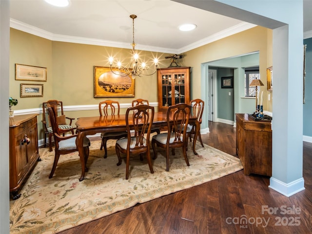 dining room with dark hardwood / wood-style flooring, crown molding, and a chandelier