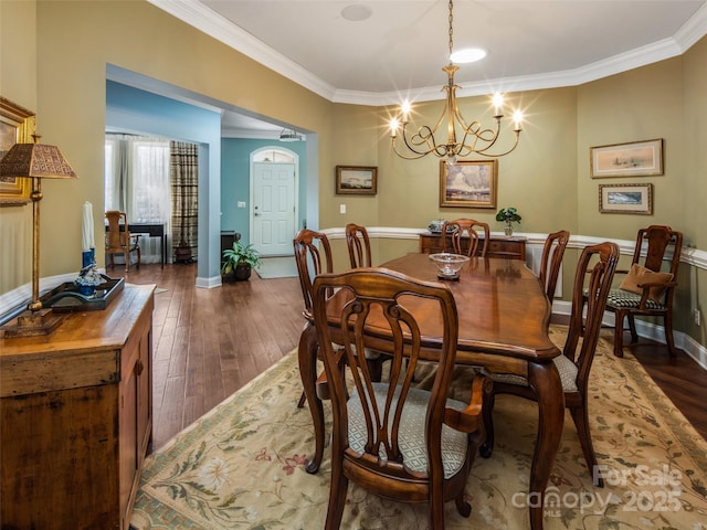 dining area featuring dark hardwood / wood-style floors, crown molding, and a notable chandelier