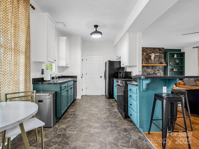 kitchen with blue cabinets, a breakfast bar, white cabinetry, a textured ceiling, and black appliances