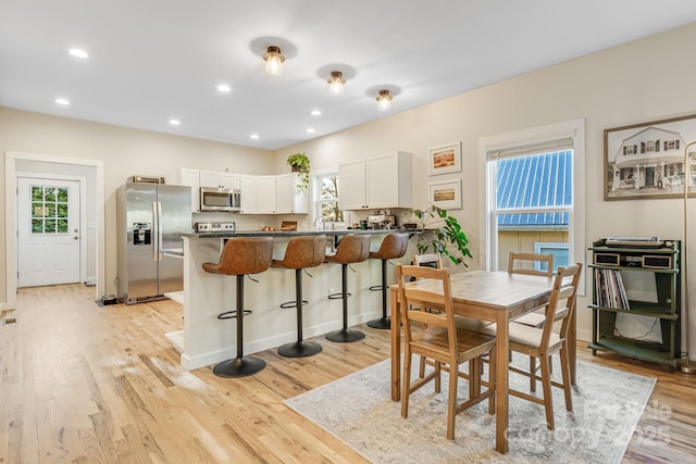 dining space with a healthy amount of sunlight, sink, and light hardwood / wood-style flooring