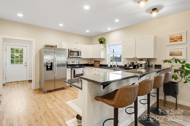 kitchen with appliances with stainless steel finishes, sink, white cabinets, and kitchen peninsula