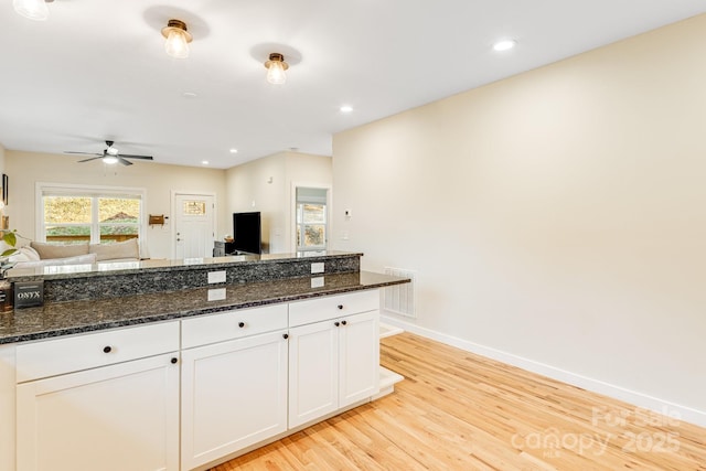 kitchen featuring ceiling fan, white cabinets, light wood-type flooring, and dark stone counters