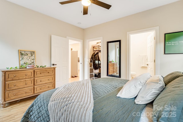 bedroom with ensuite bathroom, a walk in closet, a closet, ceiling fan, and light hardwood / wood-style floors