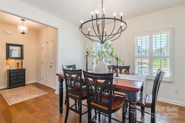 dining space featuring a chandelier, wood finished floors, and baseboards