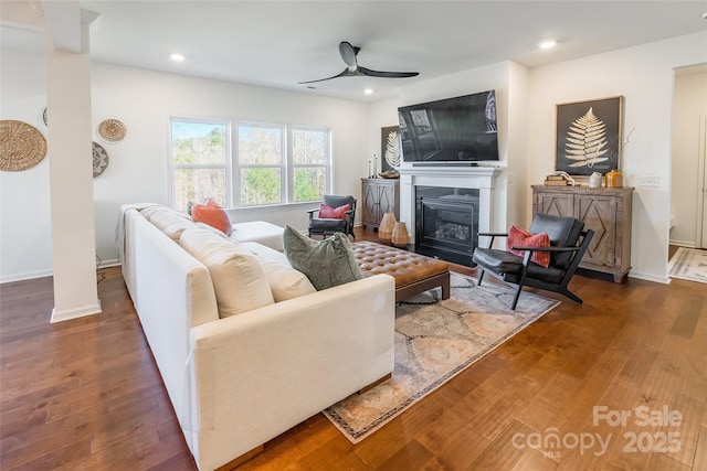 living room featuring ceiling fan, dark wood finished floors, a glass covered fireplace, and recessed lighting