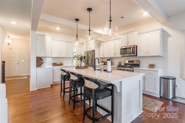 kitchen featuring visible vents, white cabinets, light countertops, appliances with stainless steel finishes, and decorative light fixtures