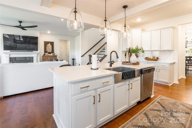 kitchen with dishwasher, open floor plan, an island with sink, and white cabinets