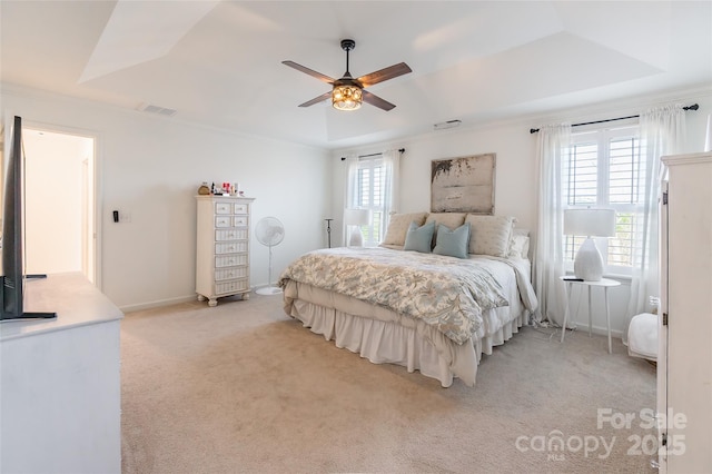 bedroom with light colored carpet, a tray ceiling, visible vents, and ornamental molding