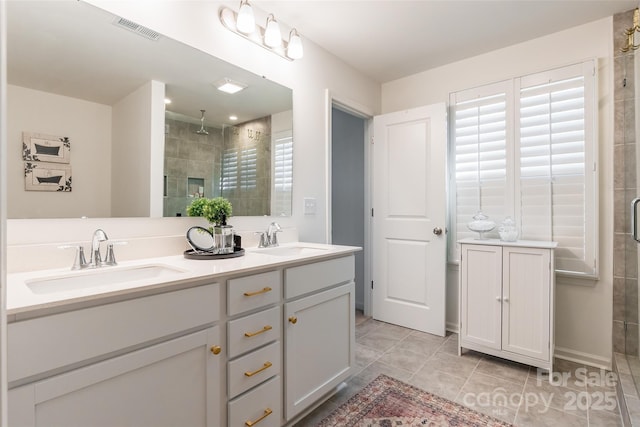 full bath featuring double vanity, a stall shower, a sink, and visible vents