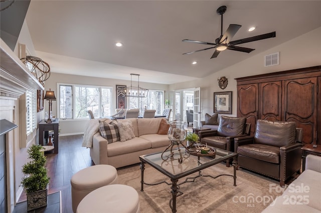 living room with vaulted ceiling, ceiling fan with notable chandelier, and light wood-type flooring