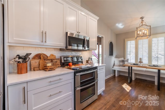 kitchen featuring an inviting chandelier, appliances with stainless steel finishes, backsplash, lofted ceiling, and white cabinets