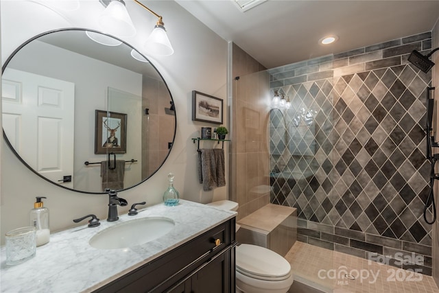 bathroom featuring toilet, vanity, and a tile shower