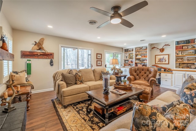 living room featuring ceiling fan, wood-type flooring, and built in shelves