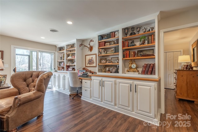 sitting room featuring dark wood-type flooring, built in features, and built in desk