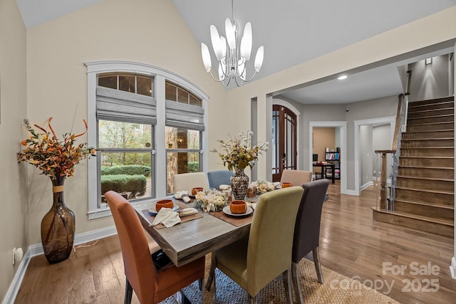 dining room with lofted ceiling, an inviting chandelier, and hardwood / wood-style flooring