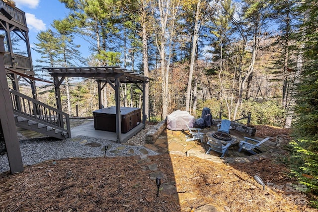 view of yard with a hot tub, a wooden deck, a patio, a fire pit, and a pergola