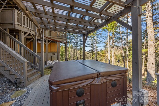 deck featuring a hot tub and a pergola