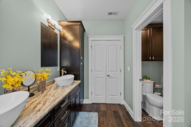 bathroom with toilet, hardwood / wood-style floors, and vanity