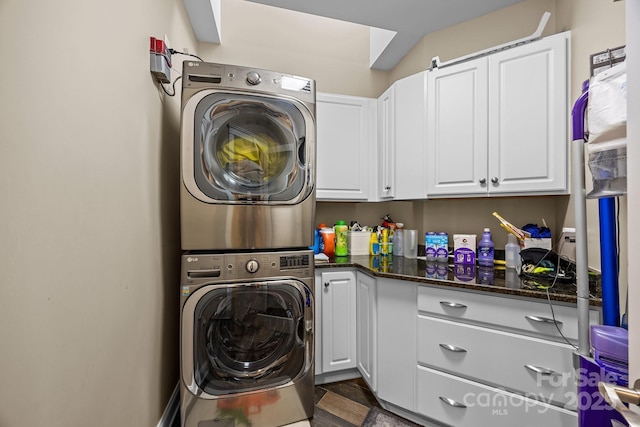 laundry area featuring stacked washer and dryer and cabinets