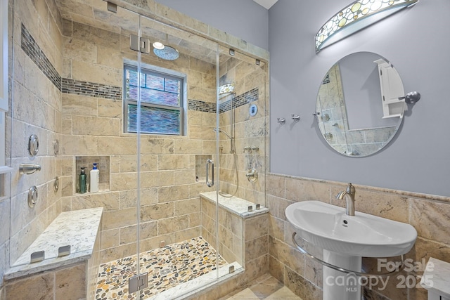 bathroom with walk in shower, tile walls, and sink