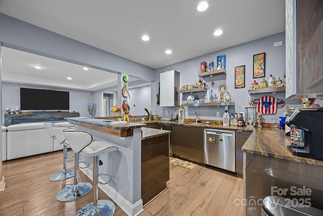 kitchen featuring dishwasher, sink, kitchen peninsula, a breakfast bar, and light hardwood / wood-style flooring