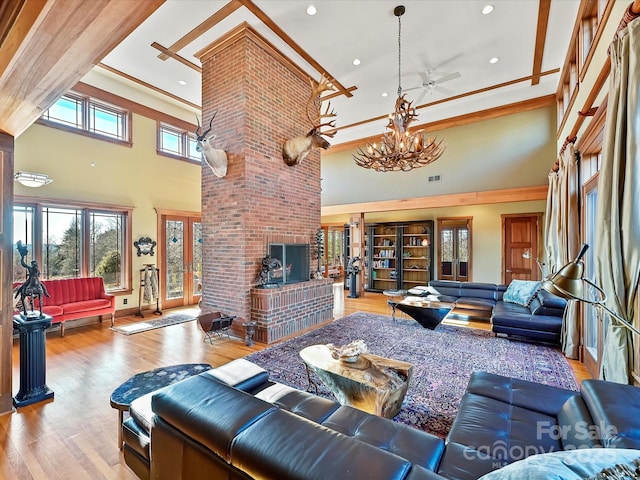 living room with a high ceiling, an inviting chandelier, a fireplace, and light hardwood / wood-style flooring