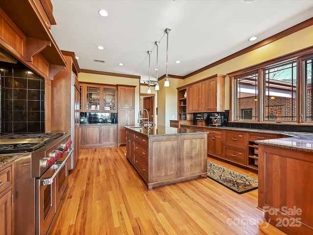 kitchen featuring sink, decorative backsplash, hanging light fixtures, double oven range, and light wood-type flooring