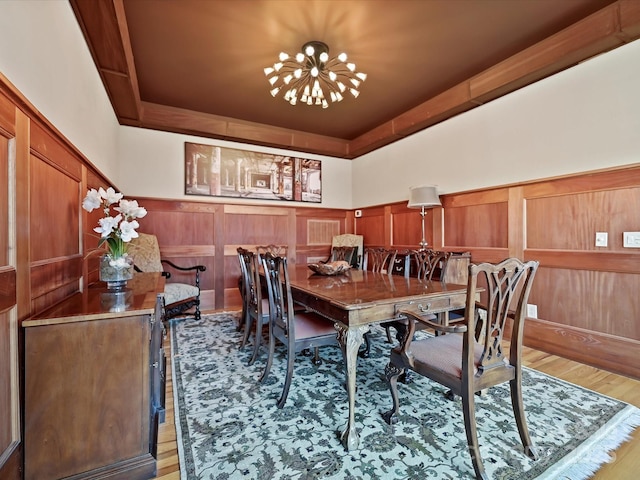 dining room featuring wood walls, a chandelier, and light hardwood / wood-style floors