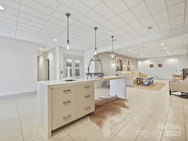 kitchen with pendant lighting, a paneled ceiling, a center island, and light tile patterned floors