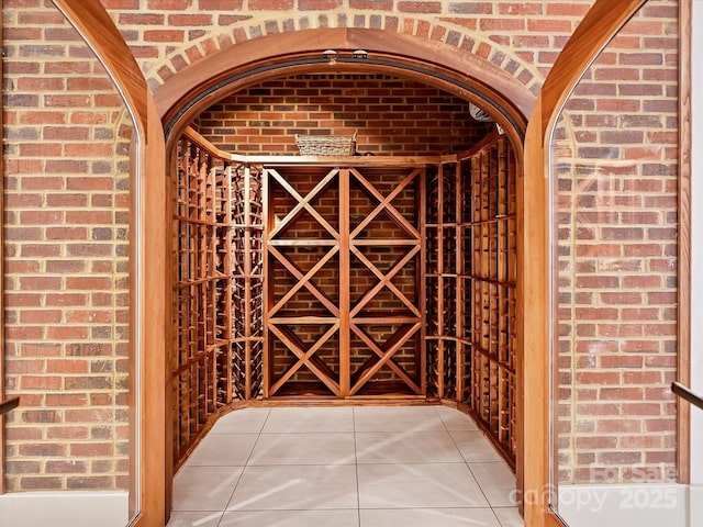 wine cellar with tile patterned floors and brick wall