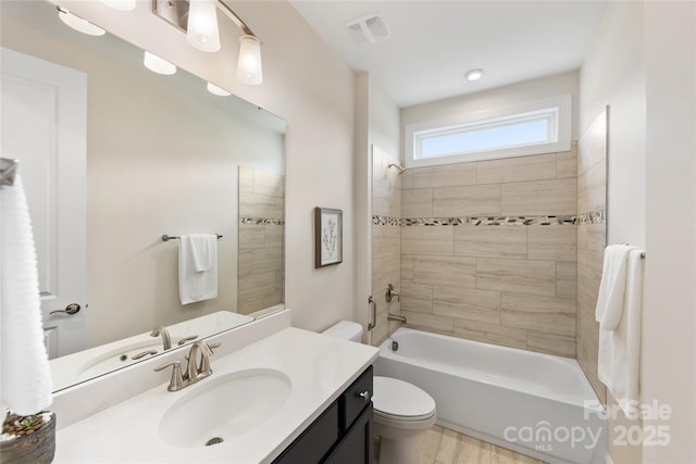 full bathroom with tiled shower / bath combo, vanity, and toilet