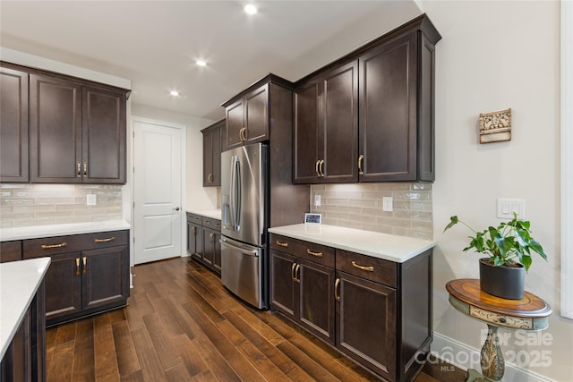 kitchen with backsplash, dark brown cabinets, and stainless steel fridge