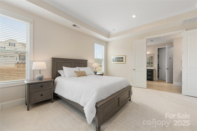 bedroom featuring crown molding, a tray ceiling, and light carpet