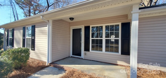 view of exterior entry with a patio area