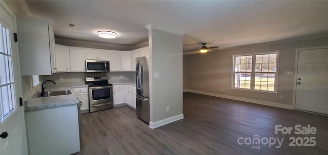 kitchen with appliances with stainless steel finishes, white cabinetry, dark hardwood / wood-style flooring, sink, and ceiling fan