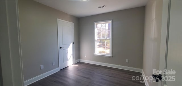 spare room featuring dark hardwood / wood-style flooring and plenty of natural light