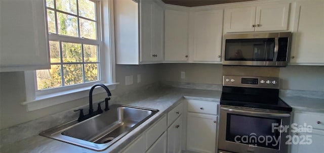 kitchen with plenty of natural light, appliances with stainless steel finishes, white cabinets, and sink