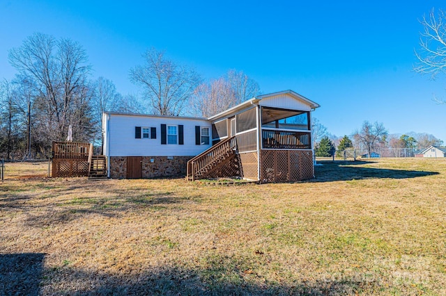 rear view of house featuring a yard and a sunroom