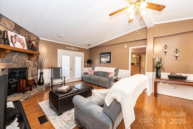 living room with lofted ceiling, crown molding, a fireplace, wood-type flooring, and french doors