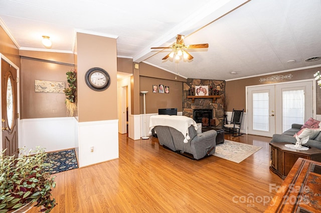 living room featuring a fireplace, ornamental molding, lofted ceiling with beams, french doors, and light wood-type flooring