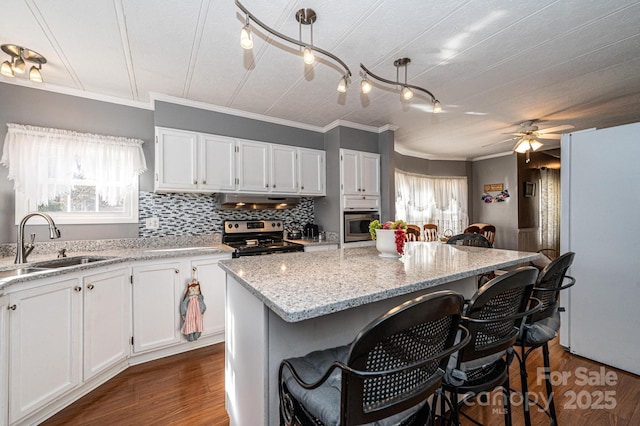 kitchen featuring sink, decorative light fixtures, a center island, appliances with stainless steel finishes, and white cabinets