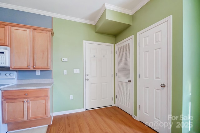 kitchen with ornamental molding, range, light brown cabinetry, and light hardwood / wood-style floors