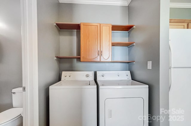 clothes washing area featuring crown molding, cabinets, and washing machine and dryer