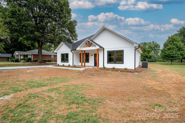 modern inspired farmhouse featuring a front yard, covered porch, and central air condition unit